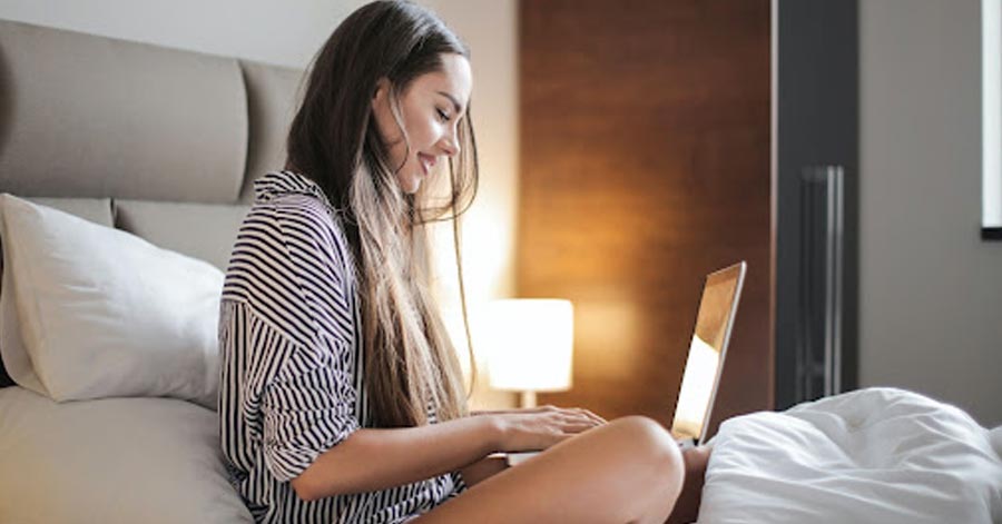 A foreign woman smiling while using a laptop.