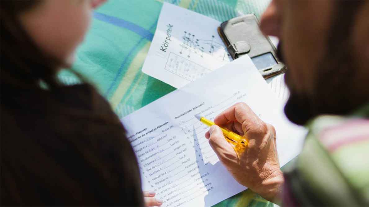 A photo of a woman, and a man who’s writing on a paper